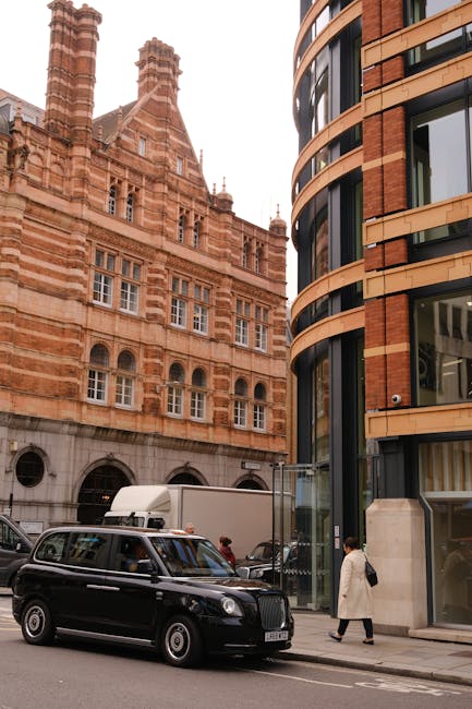 A red double-decker bus traveling along a city street surrounded by tall, historic and modern office buildings in London. The scene includes pedestrians walking on the sidewalk and a cityscape in the